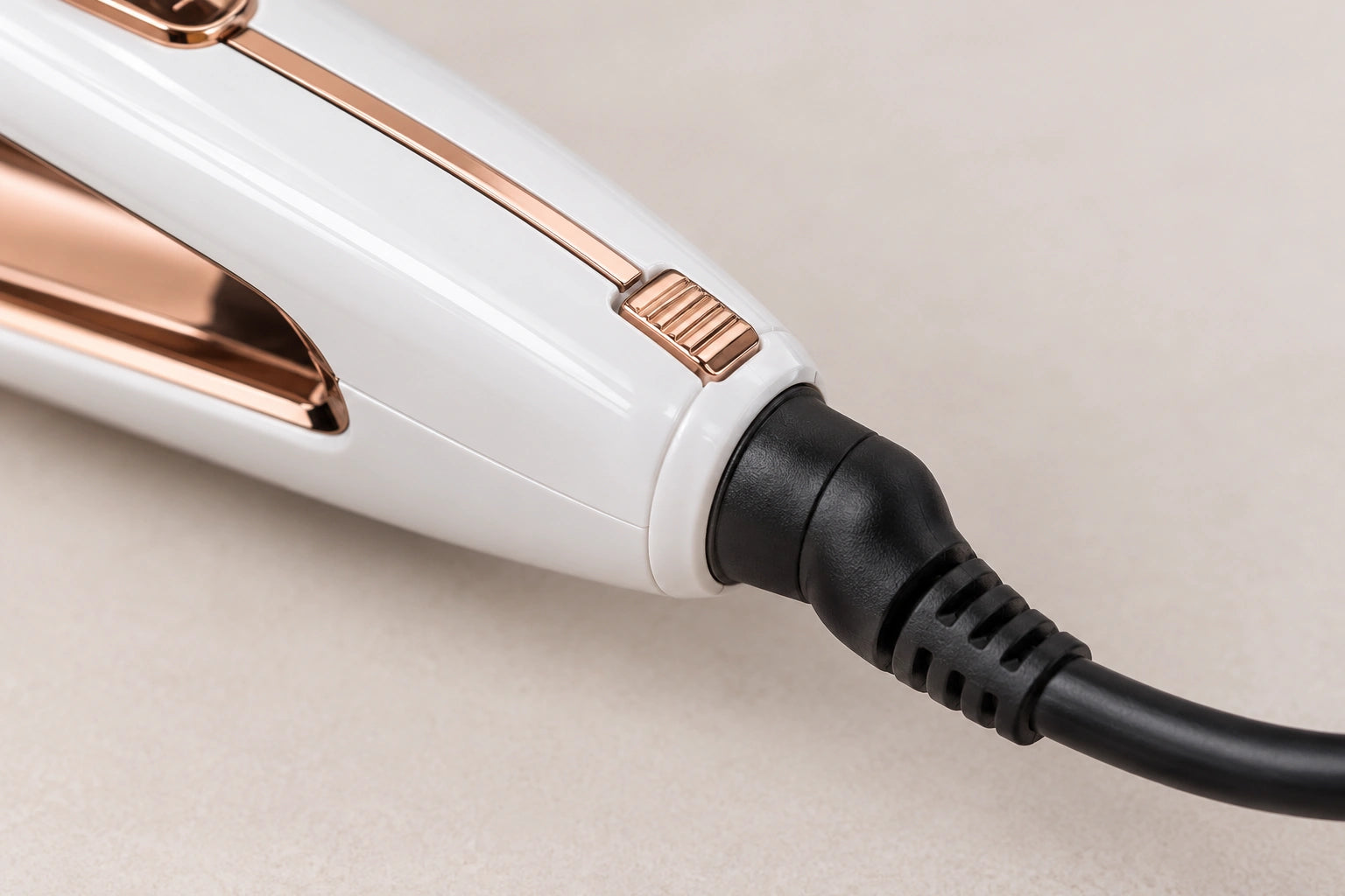 Close-up of the 1092S tail end showing the small rose-gold one-button lock and the 360-degree swivel cord joint with black cord
